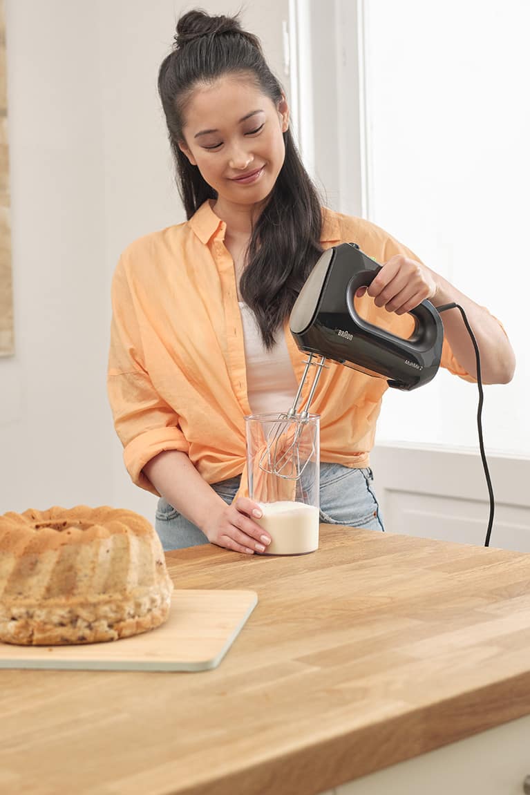 Young woman beating cream with a Braun MultiMix 2 Hand mixer