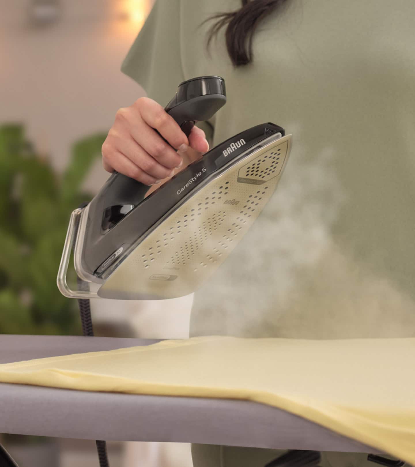 Braun CareStyle 5 Steam generating iron, black, in use with visible steam.